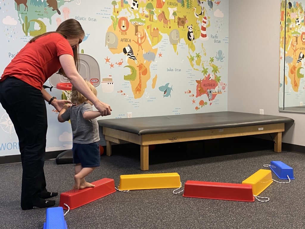 therapist help toddler on balance beam