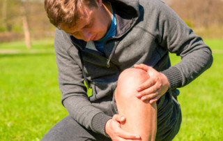 Man crouches down holding his knee