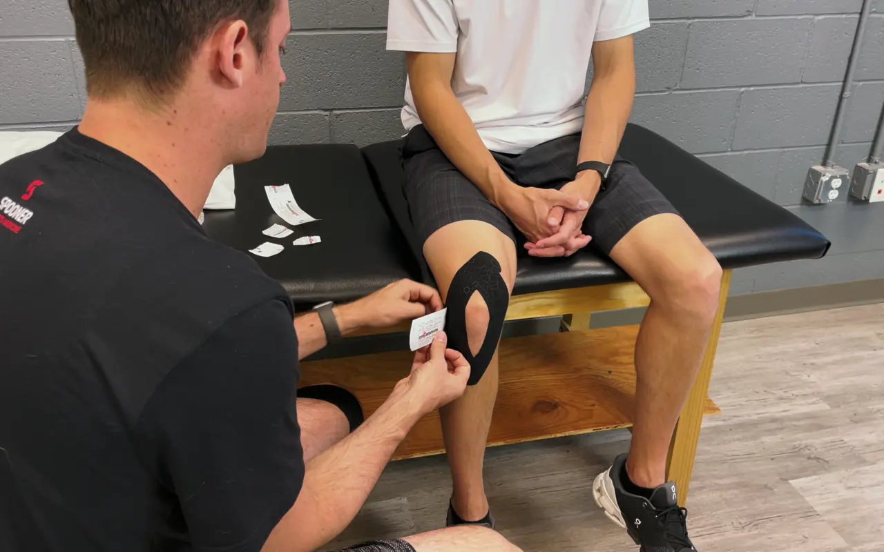 A man getting kinesio tape applied to hie knee.