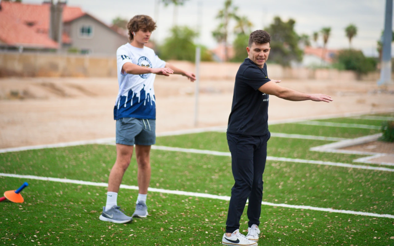 A lacrosse player trains with a physical therapist outside.