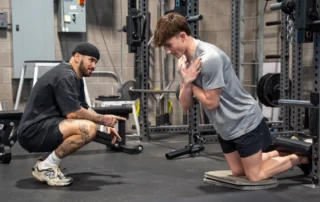 A teen athlete doing a nordic hamstring curl.