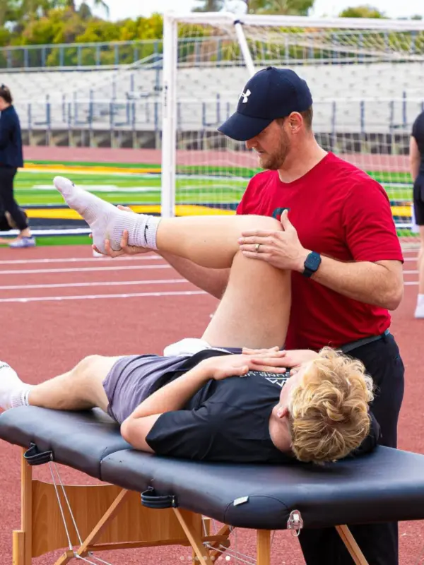 A physical therapist performs musculoskeletal manipulation on an athlete's leg.