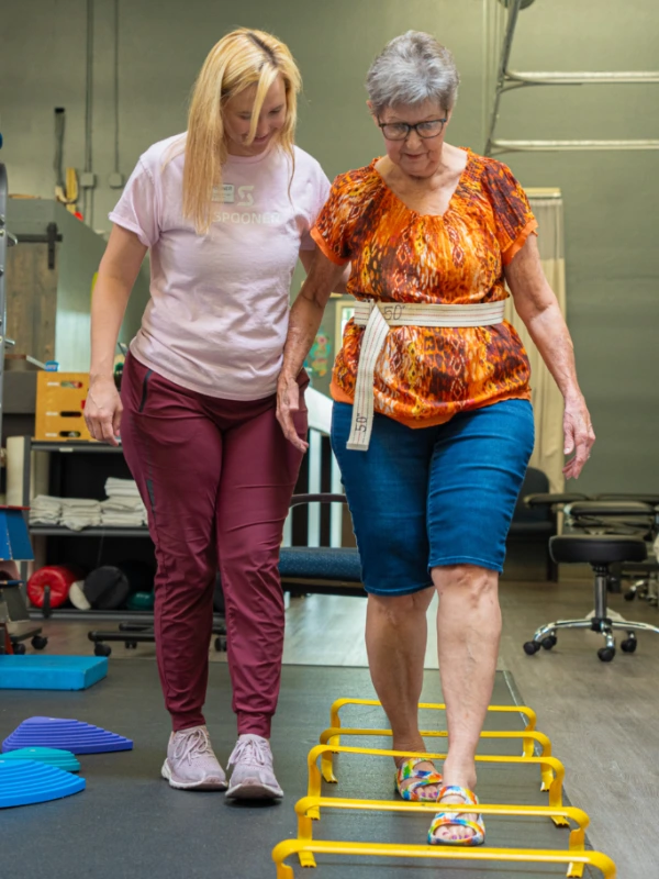 Image of an older woman steeping over ankle high hurdles.