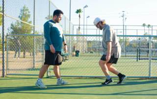 Parker Hirsch, PT, DPT, FAS coaches a male athlete on heel raise isometrics on a pickleball court.