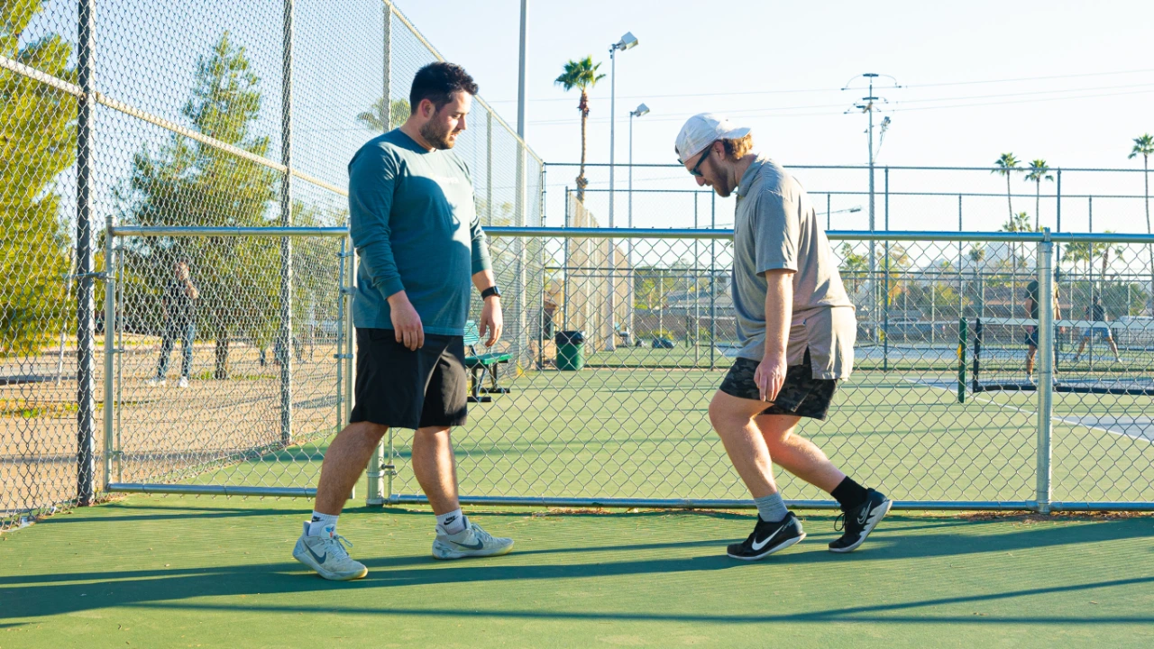 Parker Hirsch, PT, DPT, FAS coaches a male athlete on heel raise isometrics on a pickleball court.