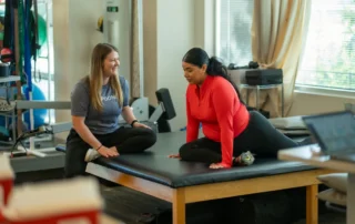 A therapist with a patient on a padded table.