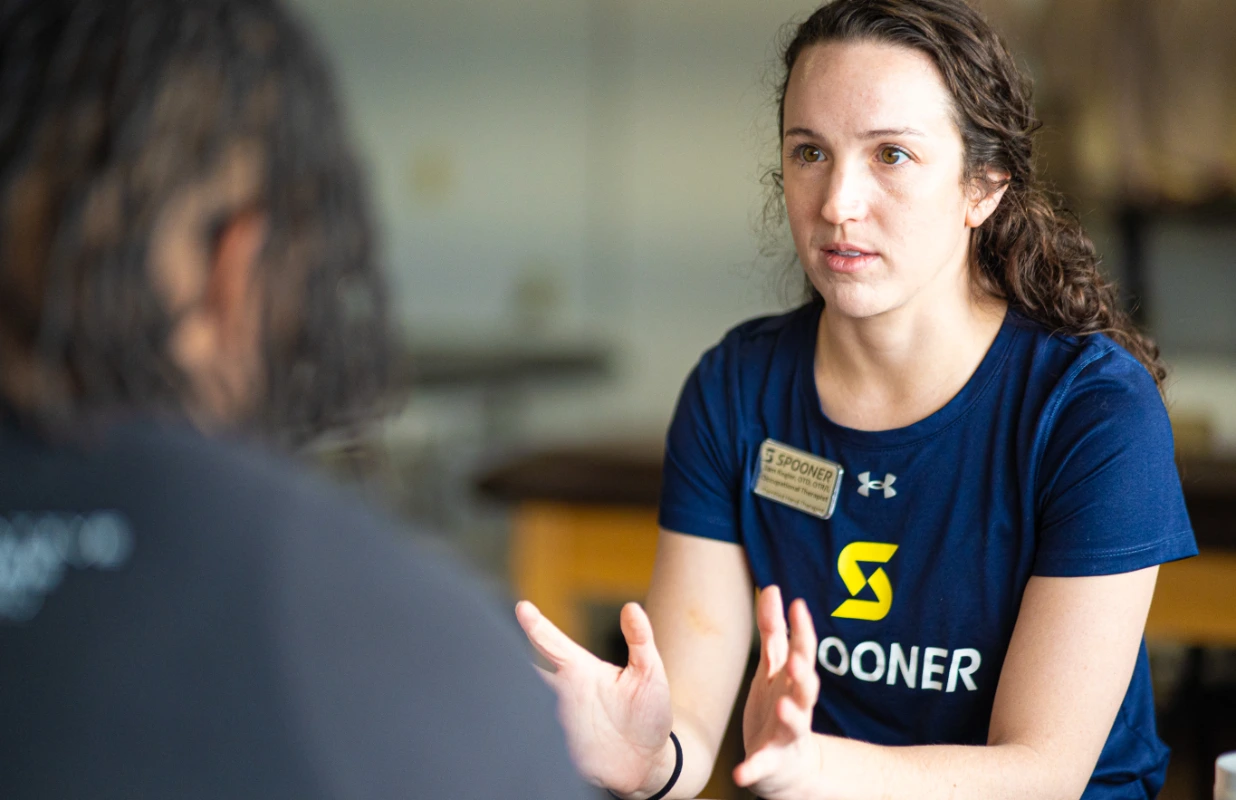 Samantha Kogler, OTR/L, OTD, CHT talking with a patient.