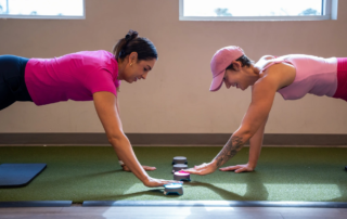 A breast health therapist working with a survivor one the floor with Blazepods.