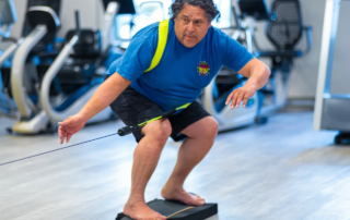 Man on a skateboard base sitting on top of a foam pad practicing his balance.