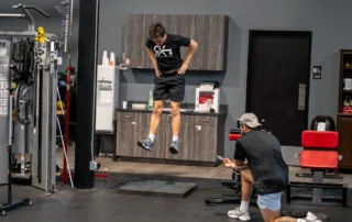 An athlete using a force plate while a athletic trainer measures the impact.