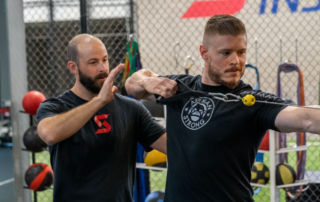 Image of Tanner Chitwood working with a crossbow athlete practicing pull back form