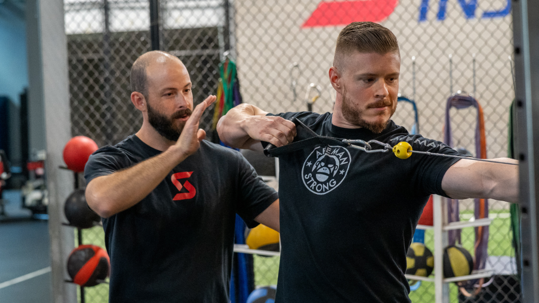 Image of Tanner Chitwood working with a crossbow athlete practicing pull back form