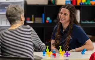 A hand therapist with an older woman using suctions cups for wrist therapy.