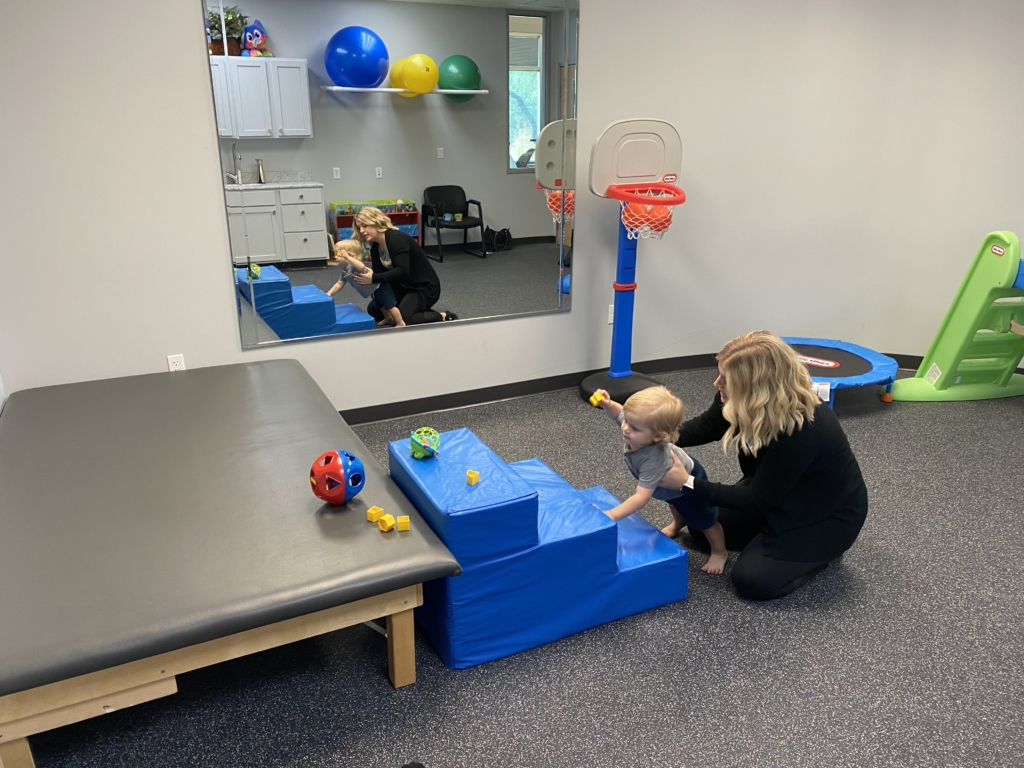 therapist helping toddler up stairs