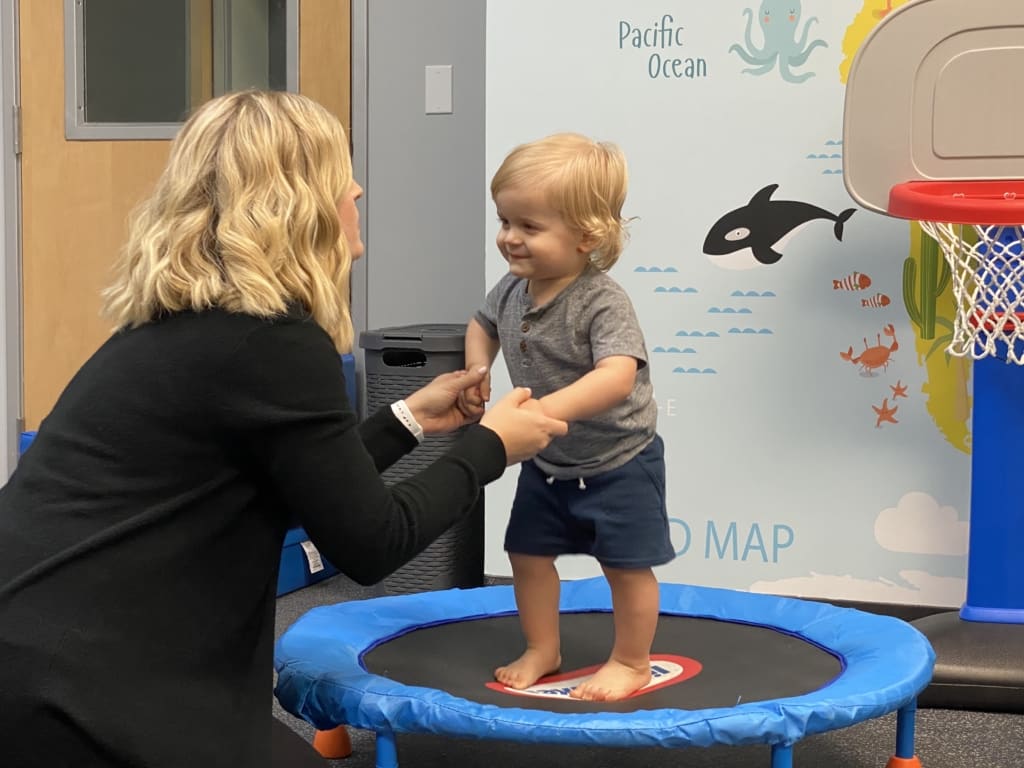 therapists with toddler on trampoline