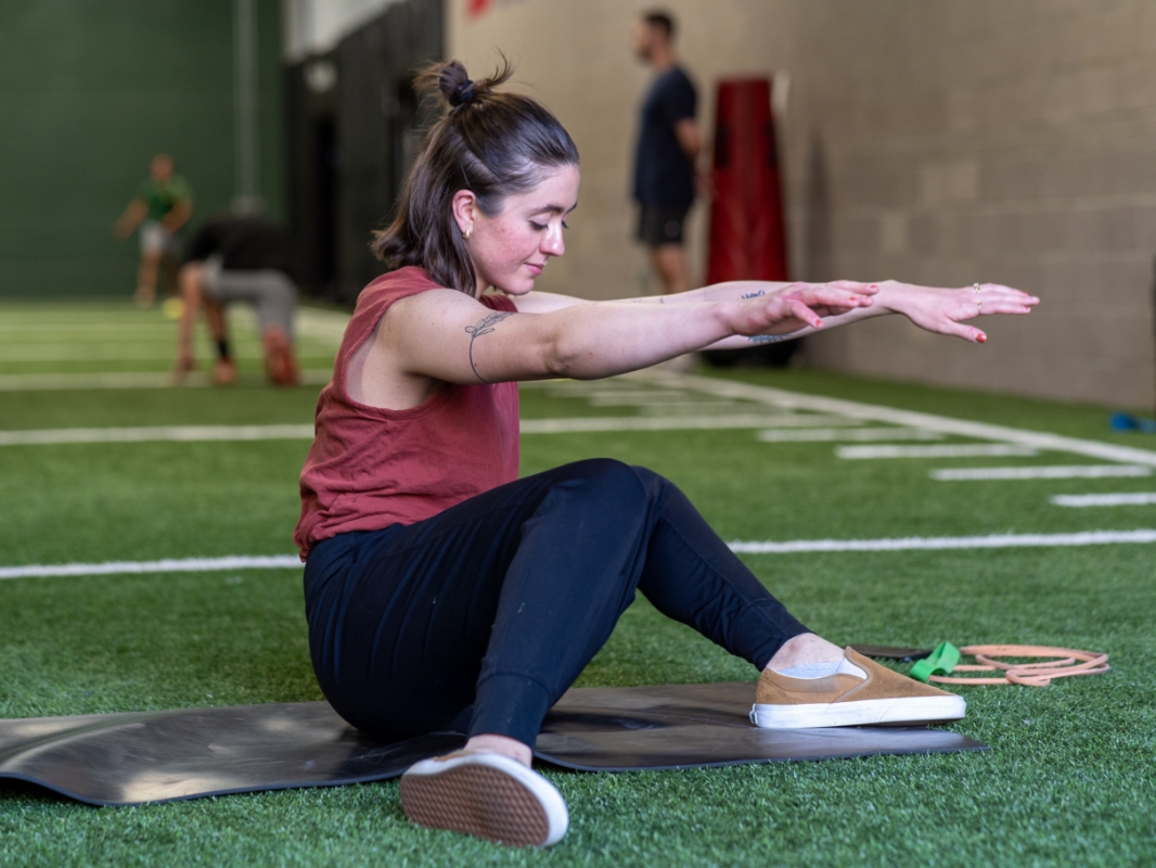 Image of a woman doing the 90/90 exercise mid rotation to the right switching leg positions.
