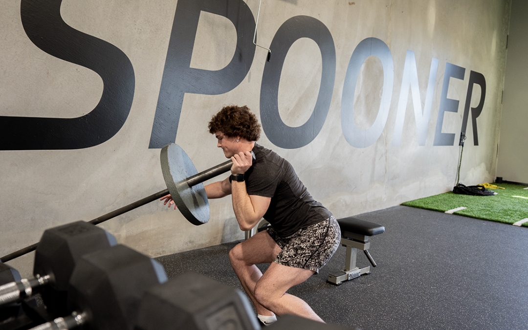 Feature image of a male athlete lifting a corner barbell.