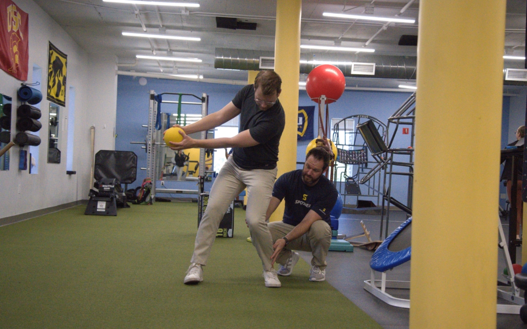 Feature image of a man getting tips on his golf swing from a physical therapist.