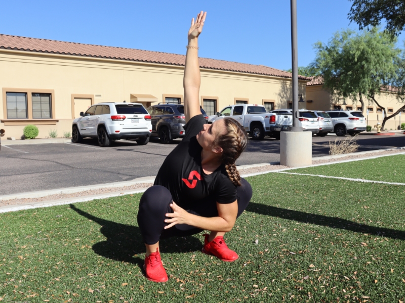 image of woman squatting and reaching right arm into the air,