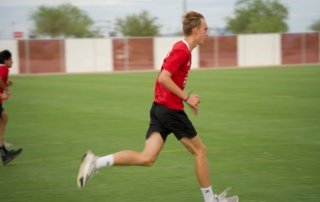 Feature image of a teenager in a red uniform running on a soccer field