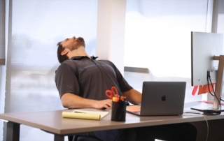 Feature image of a man sitting at a desk with his head back.