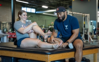 The Big Toe Blog feature image of Charles Dela Cruz examining the foot of a female athlete.