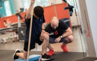 Feature image of a physical therapist helping a track athlete.