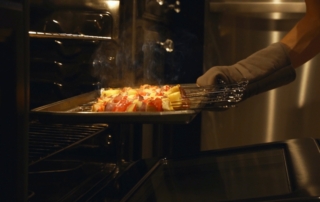 Feature image of a person pulling a tray of kebabs out of the oven.