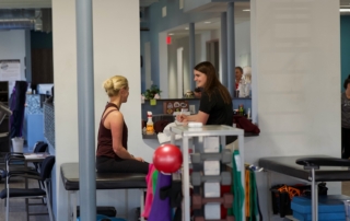 Feature image of a therapist talking to a female athlete.