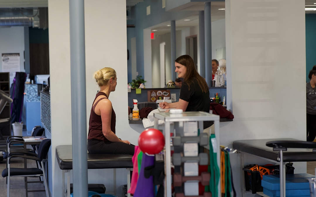 Feature image of a therapist talking to a female athlete.