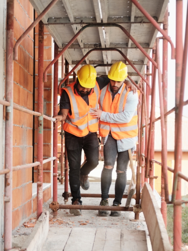 Image of one construction worker helping another construction worker after a work injury.