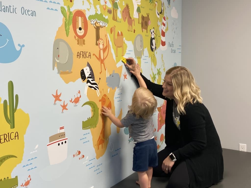 therapist and toddler play on Mural of a map