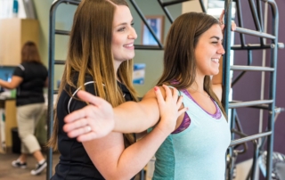A woman and a physical therapist doing a chest stretch for breast cancer recovery.